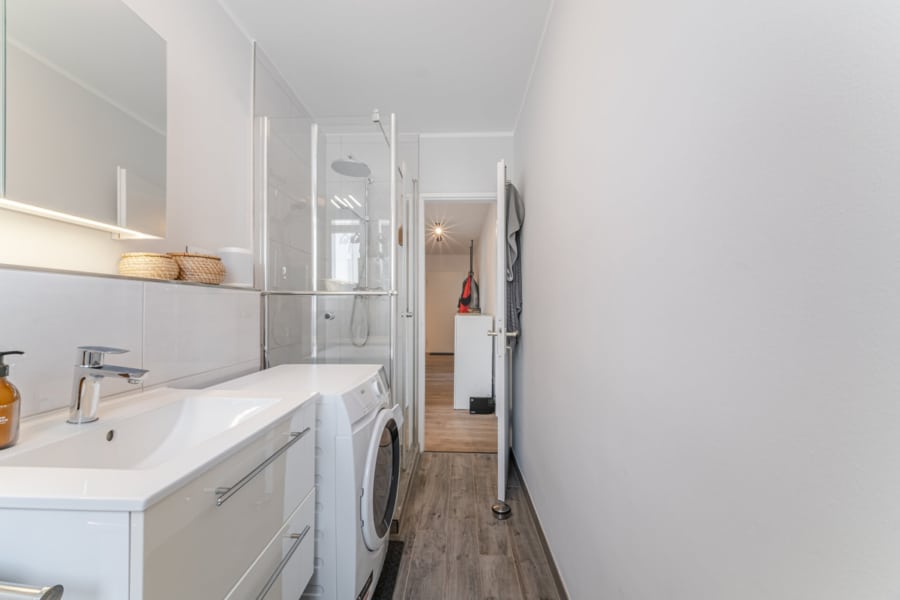 Blick durchs Bad zur Diele: Durchdacht bis ins Detail – das renovierte Bad öffnet sich zum Flur mit harmonischem Bodenbelag. - Licht, Luft & Lebensfreude – 2 Zimmer zum Verlieben in Berg am Laim