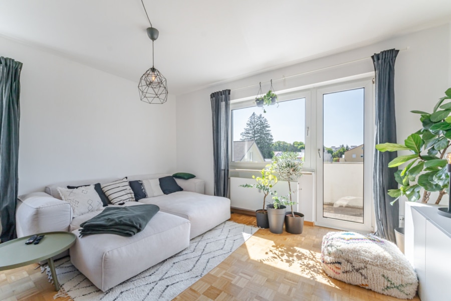 Wohnzimmer mit Zugang zum Balkon:  Lichtdurchfluteter Lieblingsplatz: Das Wohnzimmer mit Westbalkon lädt zu entspannten Abenden in der Abendsonne ein – ob mit Buch oder Lieblingsserie. - Licht, Luft & Lebensfreude – 2 Zimmer zum Verlieben in Berg am Laim