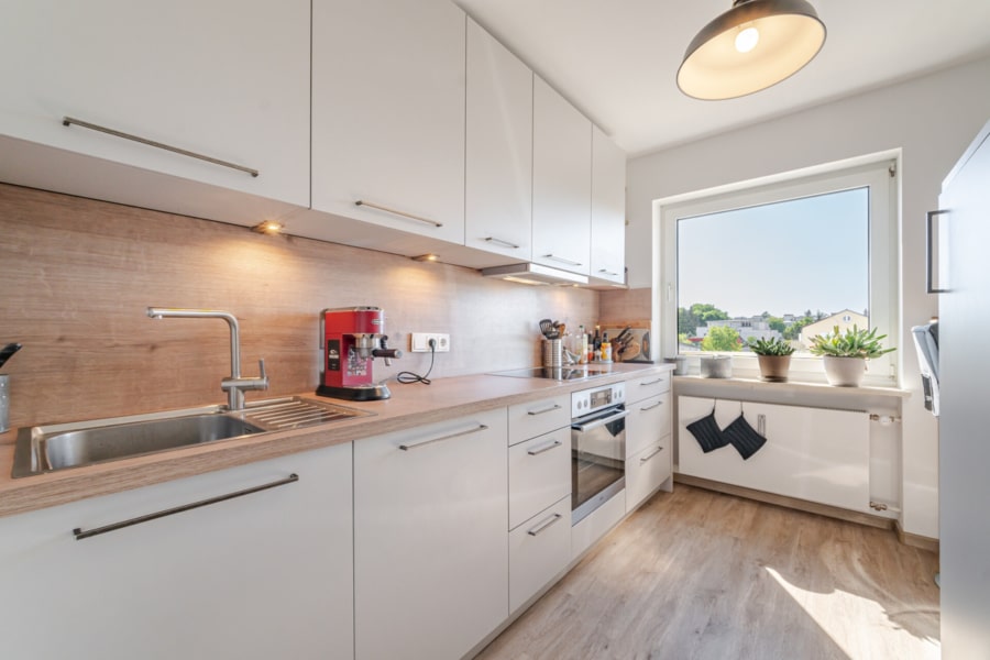 Küche – weiterer Blickwinkel mit Fenster:  Kochen mit Aussicht: Die Einbauküche punktet nicht nur mit Funktionalität, sondern auch mit schönem Blick ins Viertel. - Licht, Luft & Lebensfreude – 2 Zimmer zum Verlieben in Berg am Laim