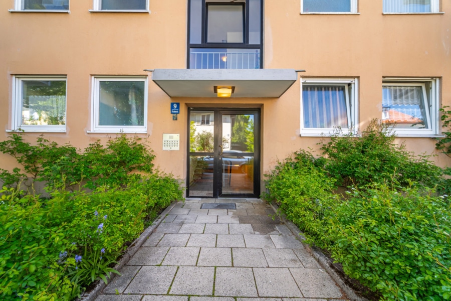 Eingangsbereich zur Wohnanlage Einladend und gepflegt präsentiert sich der Hauseingang der Pachemstraße 9 – umgeben von liebevoll angelegten Grünflächen und einem klar strukturierten Zugang - Licht, Luft & Lebensfreude – 2 Zimmer zum Verlieben in Berg am Laim
